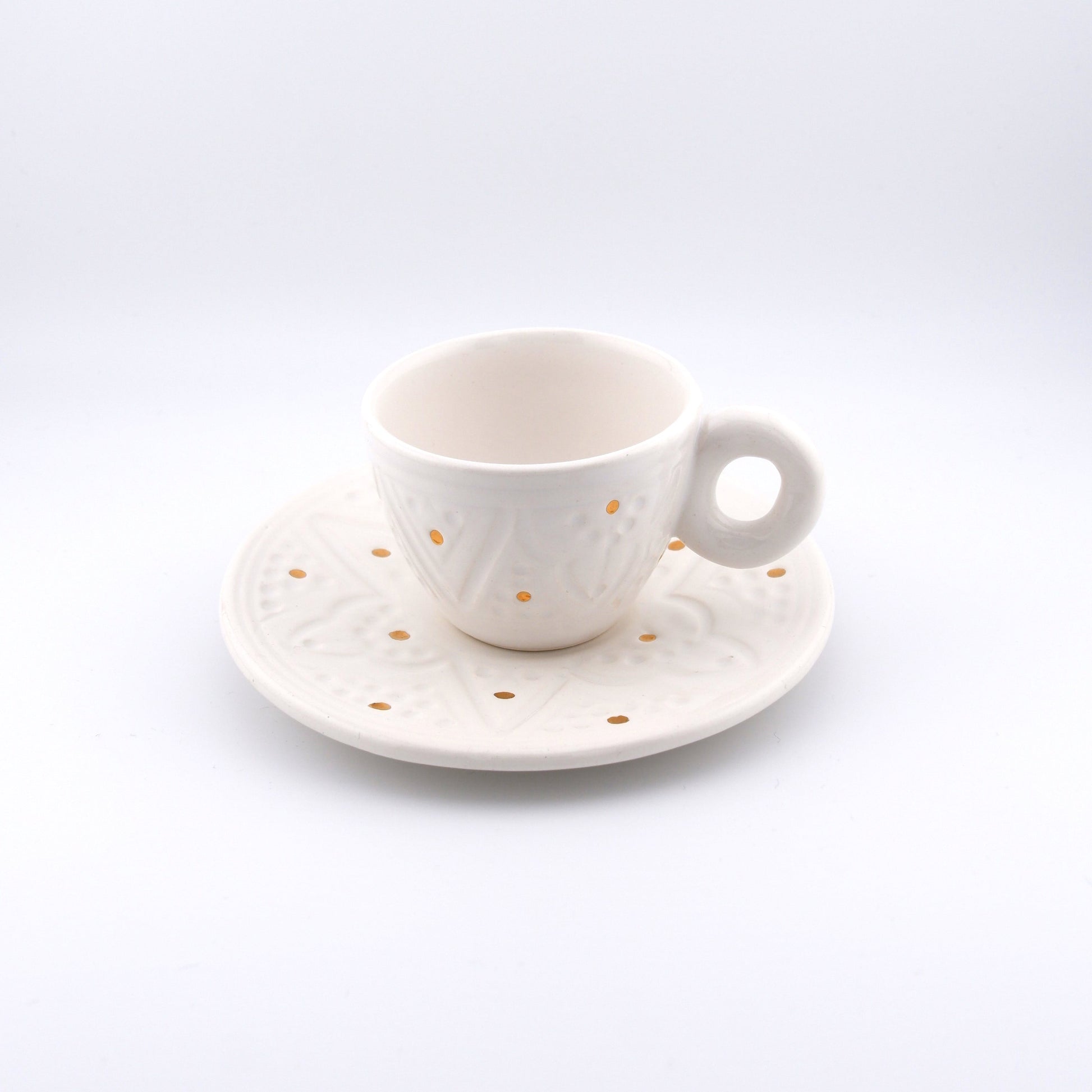 Product image of a handmade, Moroccan espresso cup with handle and matching saucer and in White color. Decorated with gold elements as well as traditional engravings. 